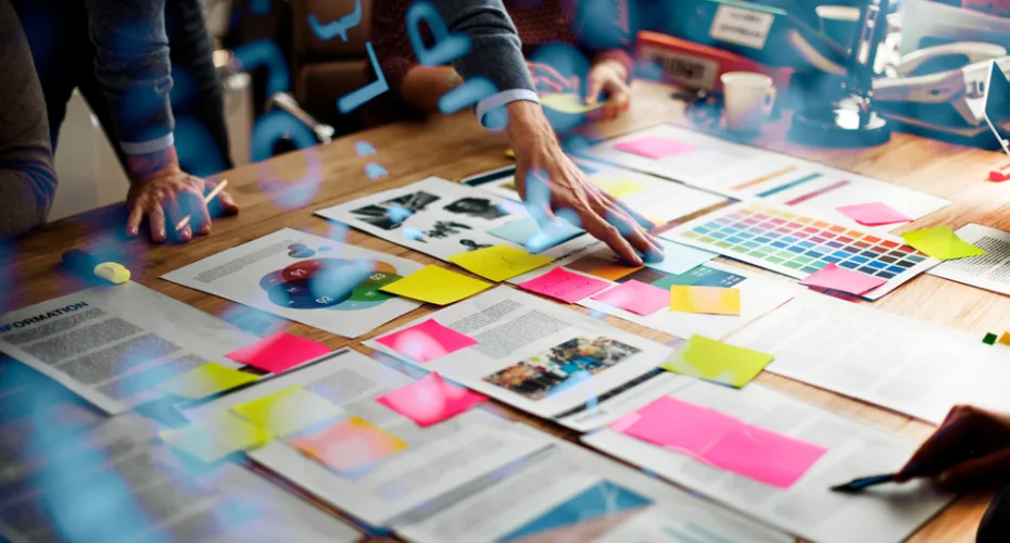 A group of people collaborating on a project, surrounded by colorful sticky notes on a table.