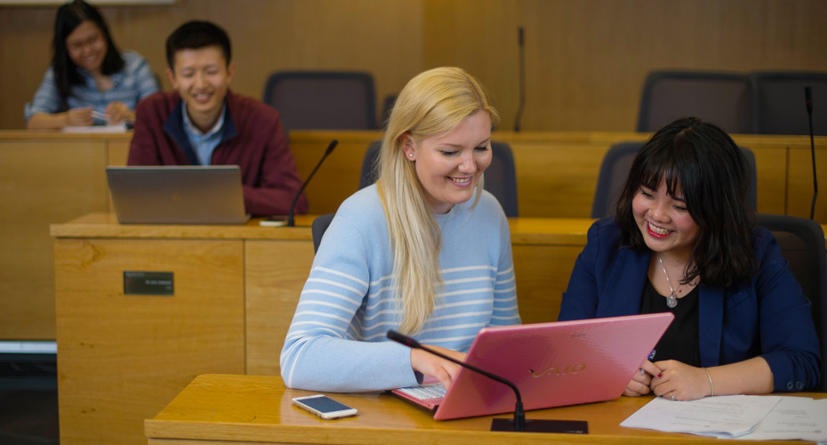 Two students working on a laptop in a business school lecture theatre